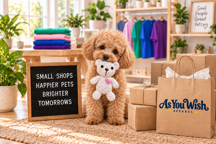 Curly-haired puppy holding a crocheted bear beside As You Wish Apparel shopping bags in a colorful boutique